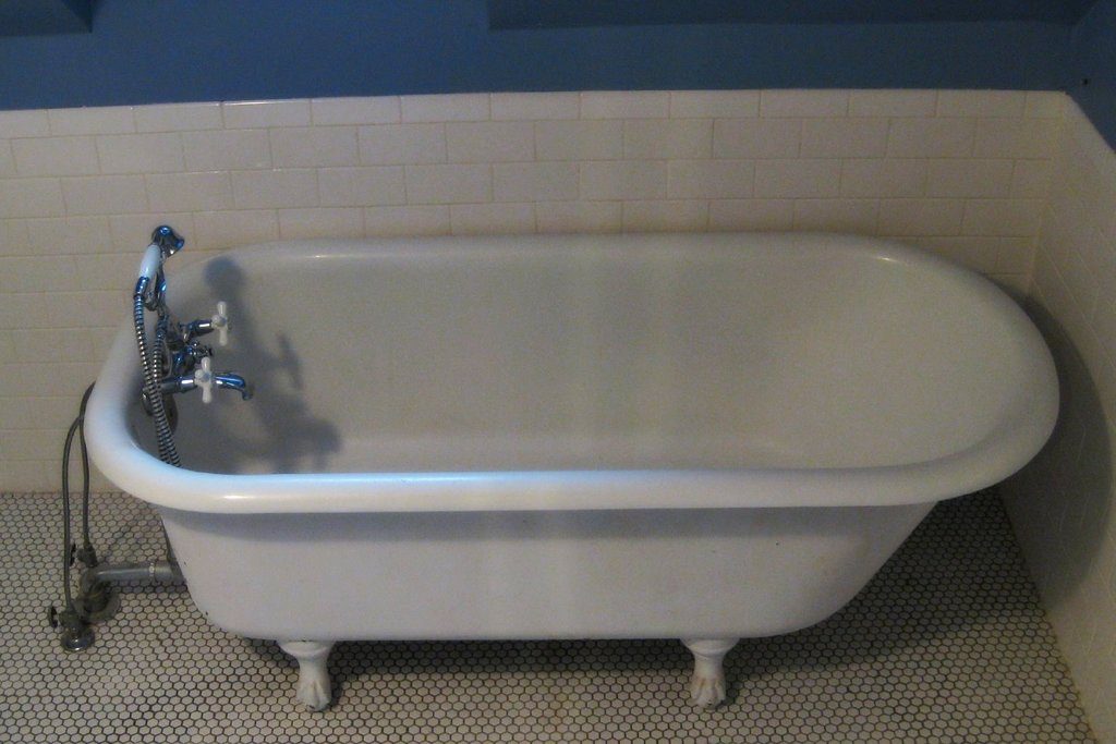 A white clawfoot bathtub with chrome taps against white wall tiles