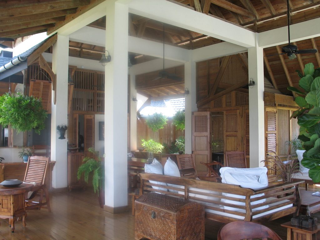 An airy open-plan living room with timber beams, white columns and wooden furniture
